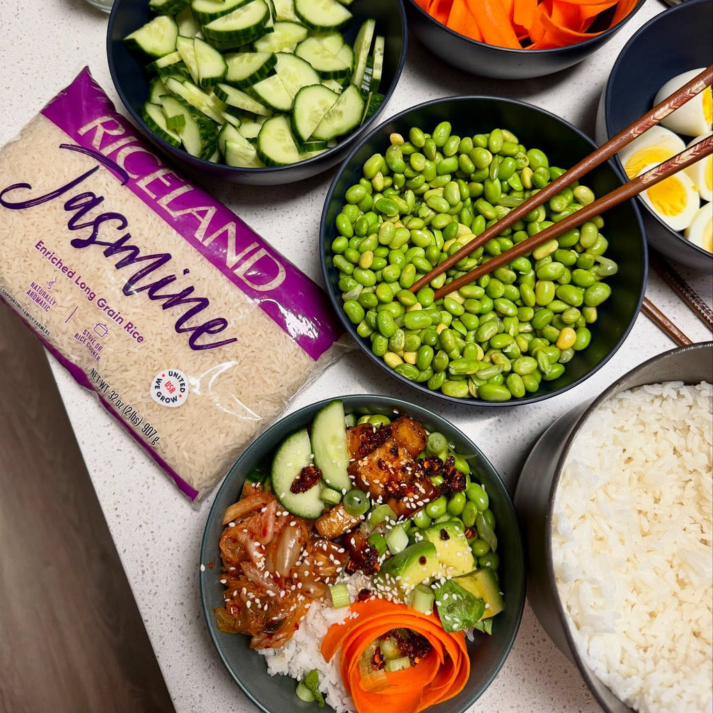 Prepared rice bowl ingredients and a package of Riceland Jasmine rice on a table.