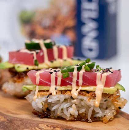 Delicate sushi rolls with tuna, avocado, and cucumber on a wooden board with a blurred background.