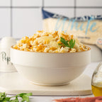 White bowl filled with rice pilaf on a white surface with a blurred background